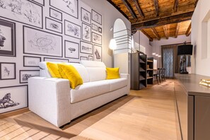 A modern living room with a white sofa, yellow cushions, and a wall adorned with framed sketches. - VIA SIMONE MAYR, 2 · Bergamo città Alta - appartamento di charme (Bergamo)