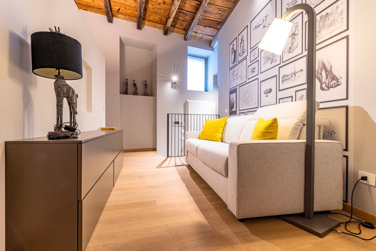 Ein modernes Zimmer mit einer Couch, einem Schreibtisch, einer Lampe und einer Wand mit gerahmten Kunstwerken.