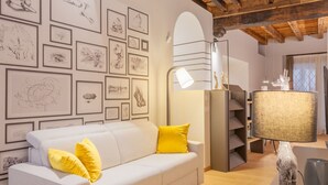 A living room with a white sofa, yellow cushions, a lamp, and framed artwork on the wall. - VIA SIMONE MAYR, 2 · Bergamo città Alta - appartamento di charme (Bergamo)