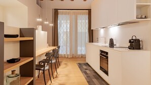 A compact kitchen with a dining area, wooden ceiling, and a view through a window with curtains. - VIA SIMONE MAYR, 2 · Bergamo città Alta - appartamento di charme (Bergamo)