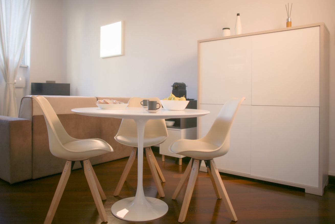 Eine moderne Küche mit einem runden Tisch, weißen Stühlen und einem Schrank.