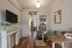 Une cuisine moderne équipée d’un téléviseur, d’une table à manger avec des chaises, et d’un couloir menant à un espace de vie.