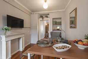 A dining area with a wooden table, a flat-screen TV mounted on the wall, a fireplace, and a mirror. - Buenos Aires 49 – Lungo la via dello shopping (Milano)