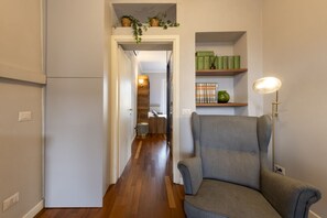 A hallway with a grey armchair, a bookshelf with books and decorative items, and a lamp. - Buenos Aires 49 – Lungo la via dello shopping (Milano)