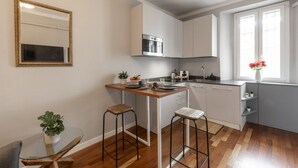 A modern kitchen with white cabinets, a stainless steel oven, a wooden countertop, and a glass table with stools. - Buenos Aires 49 – Lungo la via dello shopping (Milano)