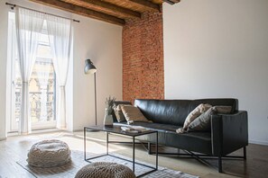 A living room with a black leather sofa, a coffee table, a lamp, and a view through a window with sheer curtains. - BUENOS AIRES, 51 - Moderno appartamento di design nel cuore di Milano (Milano)