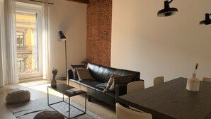 A modern living room with a leather sofa, a dining table, a floor lamp, and a brick wall. - BUENOS AIRES, 51 - Moderno appartamento di design nel cuore di Milano (Milano)