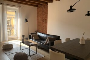 A modern living room with a leather sofa, a dining table, a floor lamp, and a brick wall. - BUENOS AIRES, 51 - Moderno appartamento di design nel cuore di Milano (Milano)
