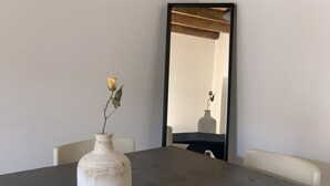A dining table with a white vase containing a single flower, a mirror on the wall, and a chair. - BUENOS AIRES, 51 - Moderno appartamento di design nel cuore di Milano (Milano)