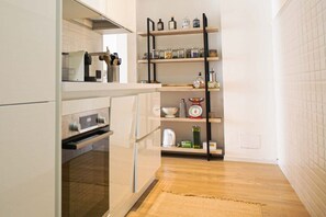 A compact kitchen with a built-in oven, a coffee machine, and a shelf with jars and kitchen utensils. - BUENOS AIRES, 51 - Moderno appartamento di design nel cuore di Milano (Milano)