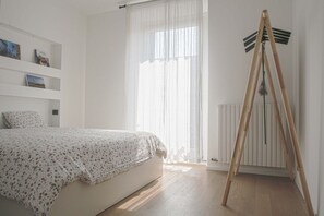 A bedroom with a bed, a radiator, a wooden easel, and a window with sheer curtains. - BUENOS AIRES, 51 - Moderno appartamento di design nel cuore di Milano (Milano)