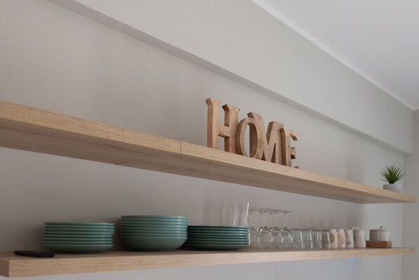 A shelf with wooden letters spelling 'HOME' above a set of green plates and glasses. - CASATI, 2 · Glamour in città tra shopping e vita notturna (Milano)