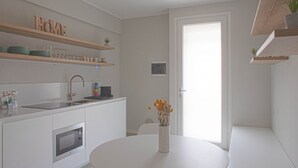 A modern kitchen with white cabinetry, a built-in oven, a sink, and a round dining table with a vase of flowers. - CASATI, 2 · Glamour in città tra shopping e vita notturna (Milano)
