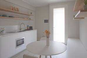 A modern kitchen with white cabinetry, a built-in oven, a sink, and a round dining table with a vase of flowers. - CASATI, 2 · Glamour in città tra shopping e vita notturna (Milano)