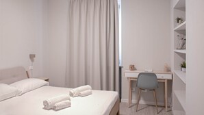Une chambre à coucher avec un lit, un bureau, une chaise et une étagère avec des plantes.