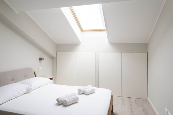 A bedroom with a skylight, a bed with white linens, and a wardrobe. - CASATI, 2 · Glamour in città tra shopping e vita notturna (Milano)