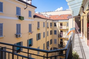 A multi-story building with balconies, air conditioning units, and a clear sky. - CASATI, 2 · Glamour in città tra shopping e vita notturna (Milano)