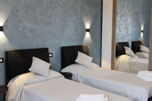 A hotel room with two beds, a small round table, and a large mirror.