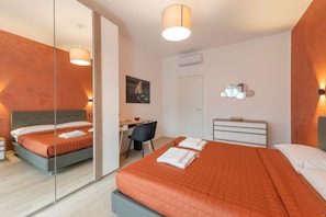 Une chambre d’hôtel comprenant un lit, un bureau, une chaise, une armoire et un miroir.