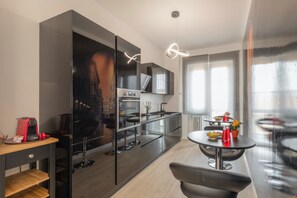 Une cuisine moderne dotée d’un grand îlot central, d’un coin repas avec une table ronde et d’un bar avec des tabourets.