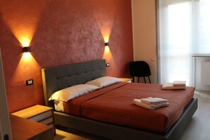 A bedroom with a bed, two wall-mounted lights, a chair, and a window.