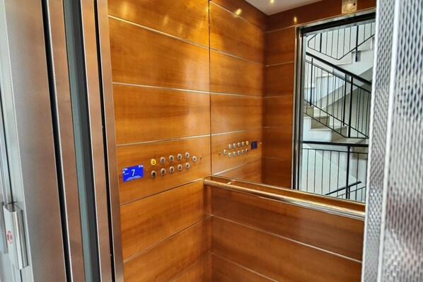 An elevator with wooden paneling and a metal handrail.