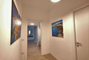 Un couloir avec deux tableaux, une porte et un luminaire.