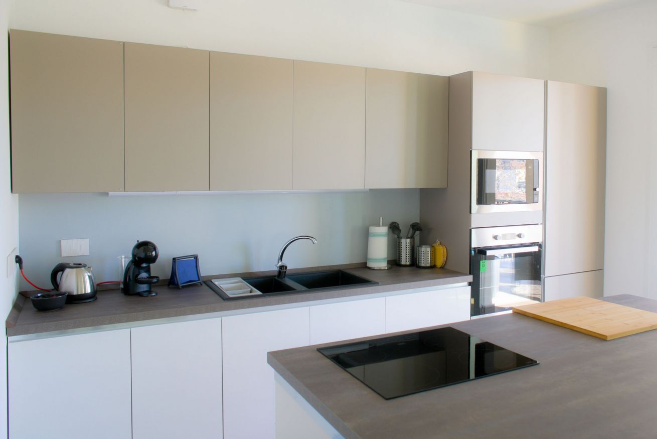 A modern kitchen with a built-in oven, a coffee maker, and a sink.