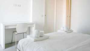 Ett hotellrum med en säng, ett skrivbord, en stol och en dörr.