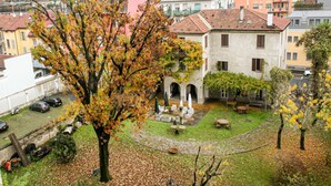 A courtyard with a tree, outdoor seating, and a building with arches.