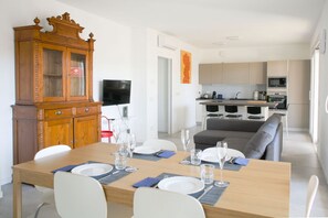 Un coin repas avec une table en bois dressée pour quatre personnes, un buffet et un téléviseur.