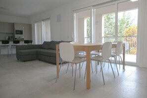 A modern living room with a dining area, a grey sofa, and a kitchen in the background. - GOVONE, 78 · Ampio e luminoso appartamento con terrazza (Milano)