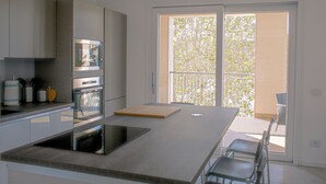 A modern kitchen with a large island, built-in appliances, and a sliding glass door leading to a balcony.