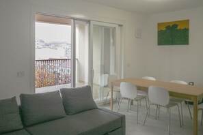 A modern living room with a sofa, a dining table with chairs, a balcony with a view of buildings, and a painting on the wall. - GOVONE, 78 · Ampio e luminoso appartamento con terrazza (Milano)