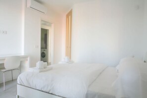 Une chambre d’hôtel moderne équipée d’un lit, d’un bureau, d’une chaise et d’un lave-linge.