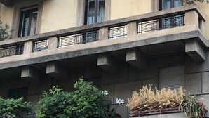 Un immeuble à plusieurs étages doté de balcons, de fenêtres et de quelques éléments de végétation.