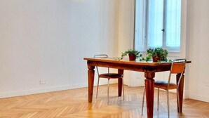 Un coin repas avec une table en bois, deux chaises et des plantes en pot.