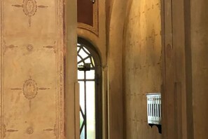 An interior corridor with arched doorways and a small window with bars. - Guercino, 8 – Renovated design apartment (Milano)