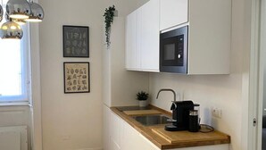 Une cuisine moderne avec des meubles blancs, un plan de travail en bois, un four à micro-ondes encastré et une machine à café.