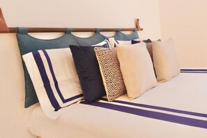 Un lit avec une tête de lit, plusieurs oreillers et une couvre-lit à rayures.