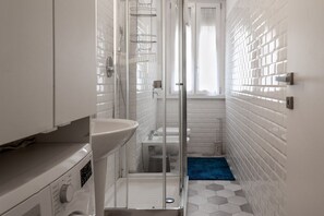 Un baño con cabina de ducha de vidrio, un lavabo y un inodoro.