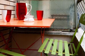 Una mesa con tazas rojas y blancas, una jarrón y un tarro de vidrio con cubitos de azúcar.