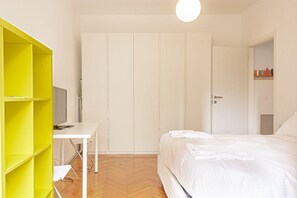 Un dormitorio con cama, escritorio, televisor y armario.