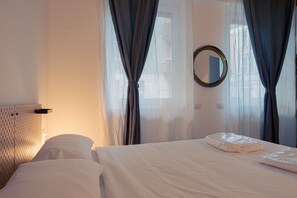 Hotellihuone, jossa on sänky, pyöreä peili ja läpikuultavat verhot.