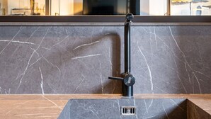 A bathroom with a marble sink, a black faucet, and a visible drain. - Paganini boutique apartment (Milano)