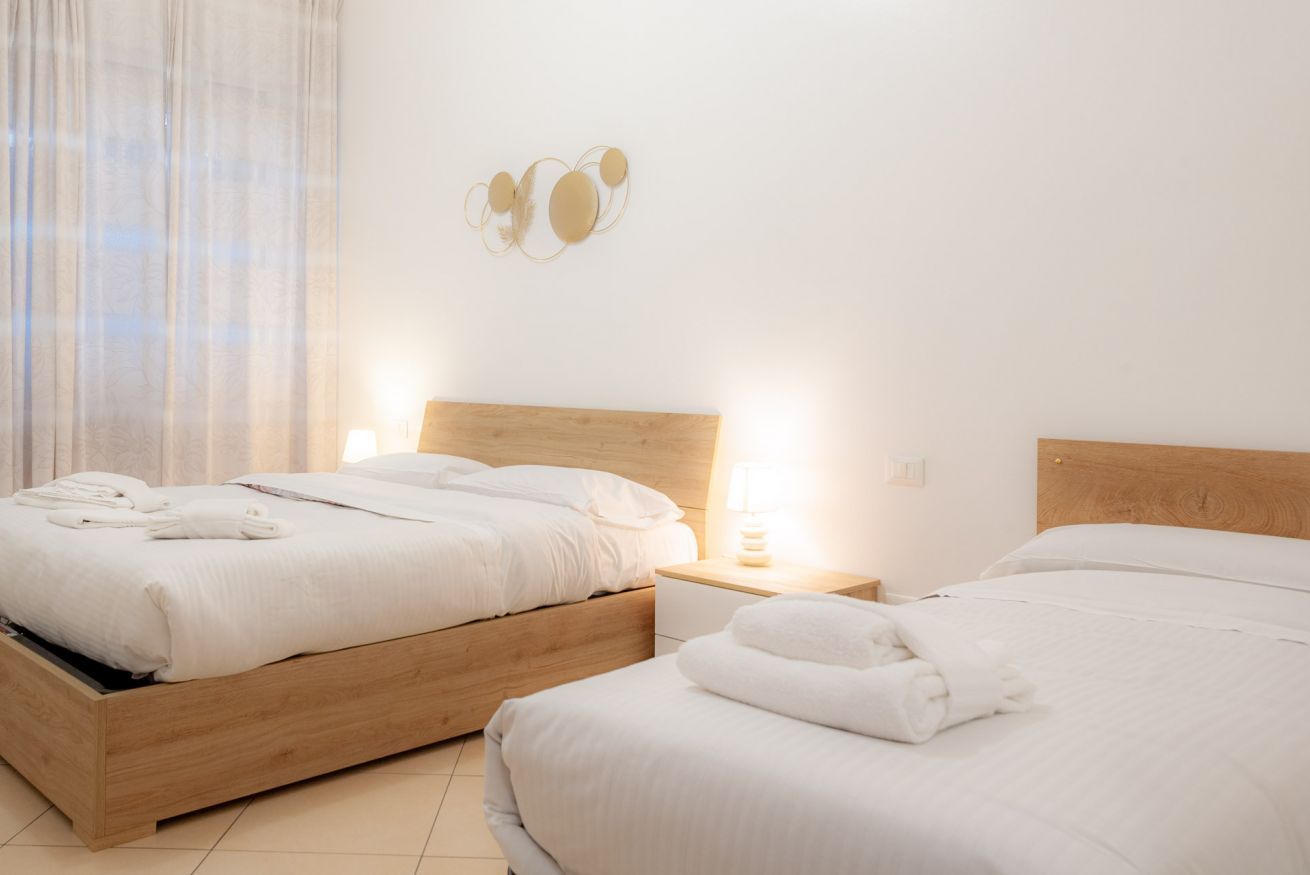 Dos camas con cabeceros de madera, ropa de cama blanca y toallas.