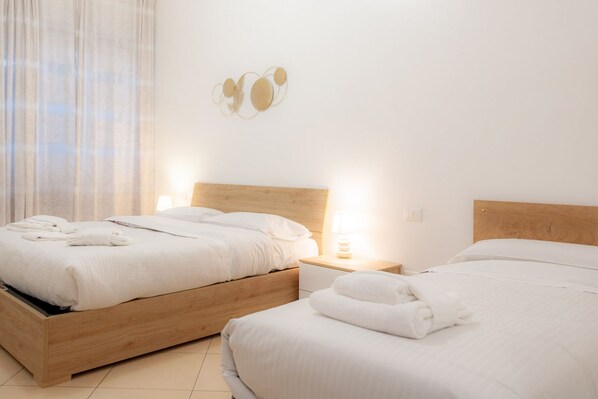Two beds with wooden frames, white bedding, and towels.
