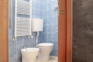 Un baño con inodoro, bidé y un perchero para toallas.