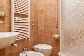 A bathroom with a sink, bidet, toilet, and a shower enclosure.