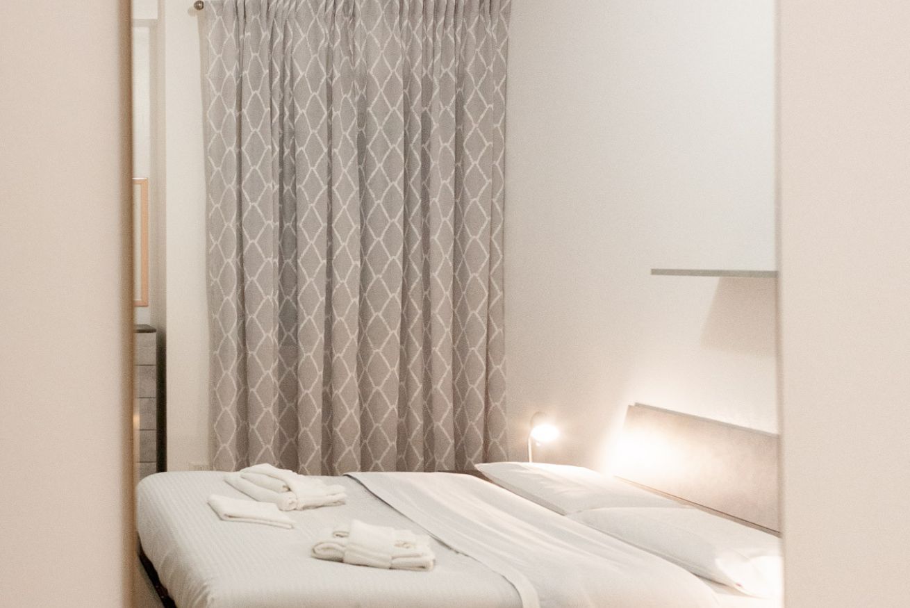 Una habitación de hotel con una cama, cabecera y cortina.